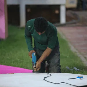 Person using a power tool on a white surface outdoors 